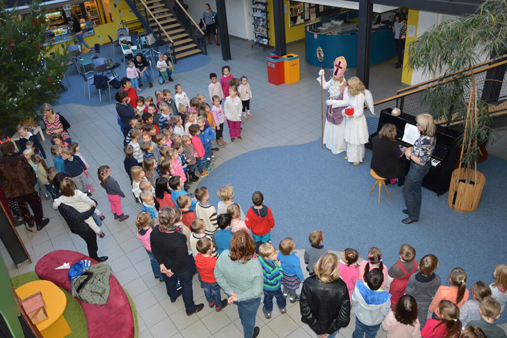 Skupina dětí z mateřské školy sedící na podlaze a sledující představení.